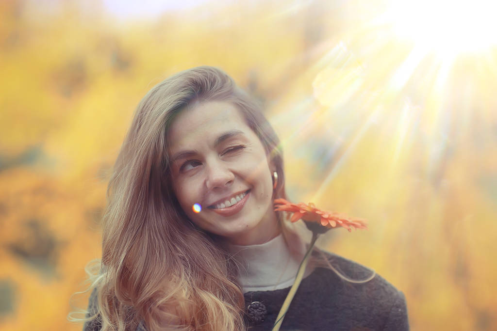 Herbstporträt einer schönen Blondine mit einer Blume, Model posiert mit positivem Lächeln - Foto, Bild