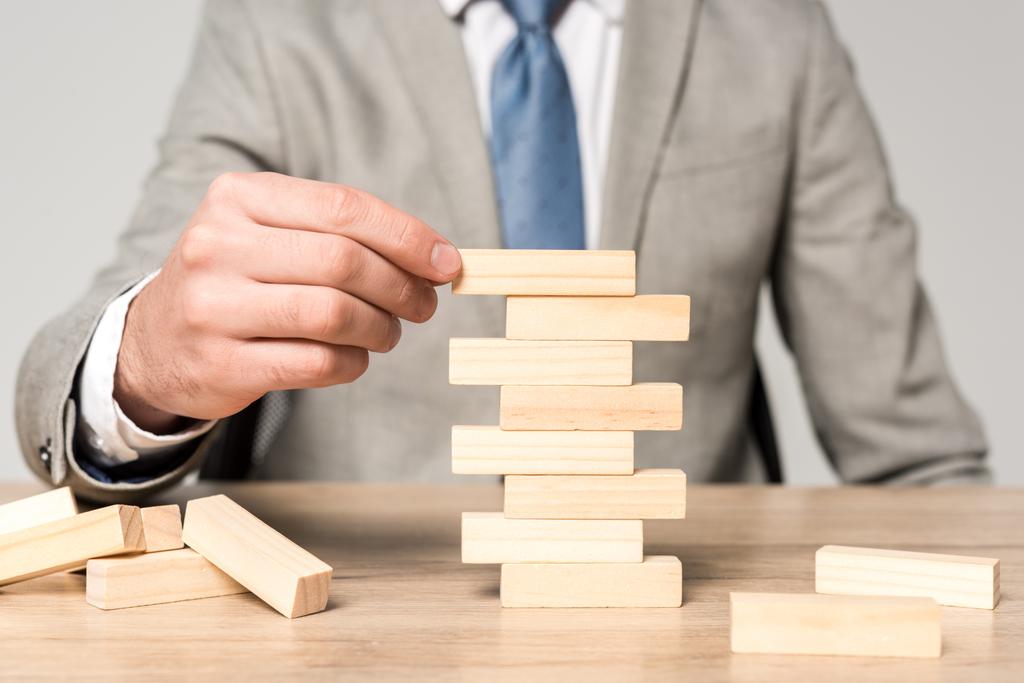 обрізаний вид бізнесмена, який грає блоки дерев'яна вежа гра ізольована на сірому
 - Фото, зображення