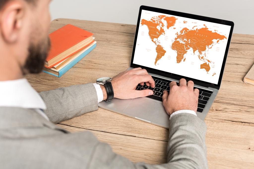 обрезанный вид бизнесмена с помощью ноутбука с картой мира на экране изолированы на сером
 - Фото, изображение