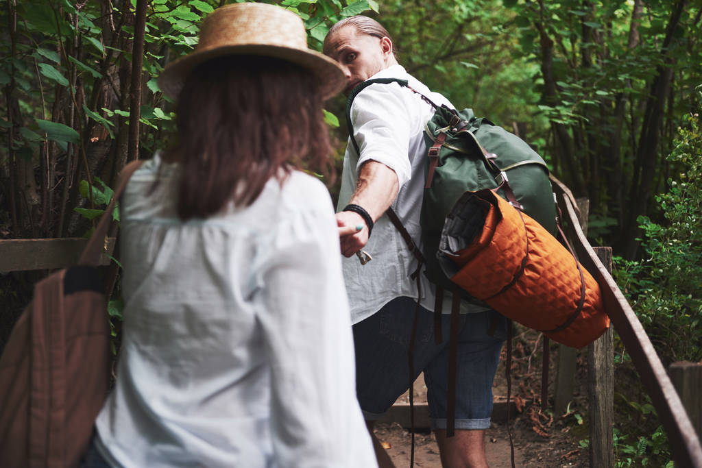 Sırt çantalı iki doğa yürüyüşçüsü. Bir yaz günü yürürken el ele tutuşan erkek ve kadın.. - Fotoğraf, Görsel