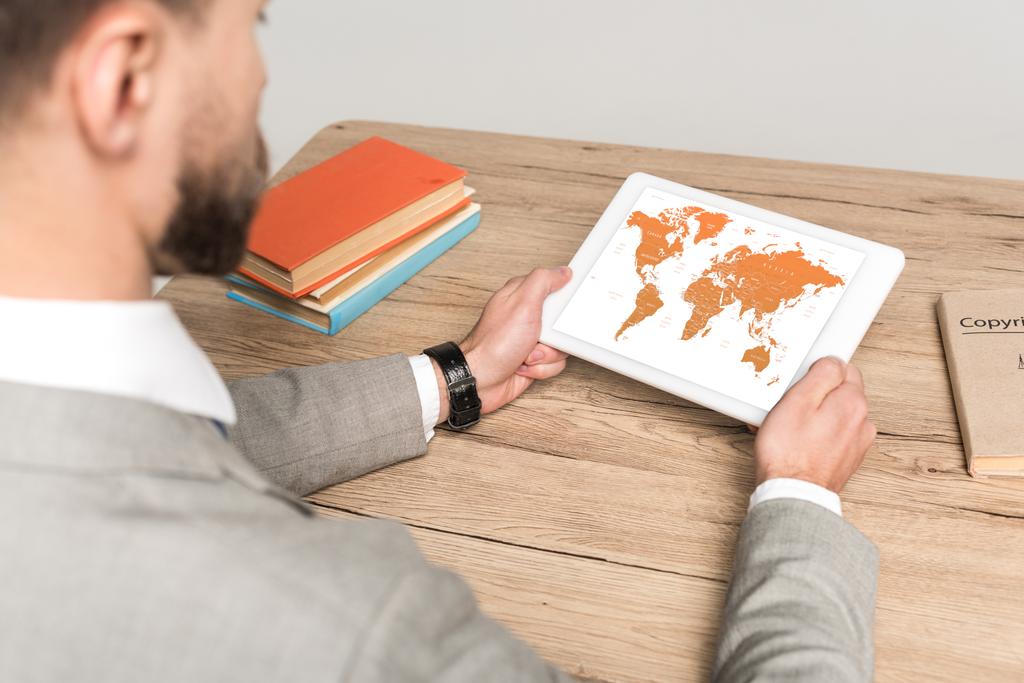 vista recortada de hombre de negocios utilizando tableta digital con mapa del mundo en la pantalla aislado en gris
 - Foto, imagen