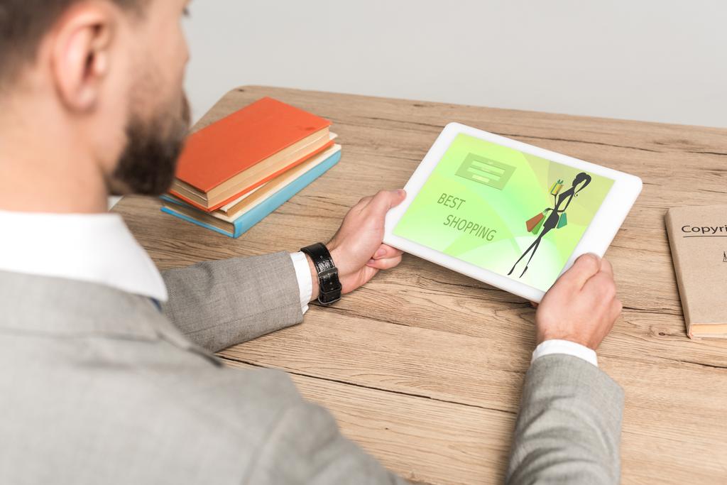 vista parziale dell'uomo d'affari che utilizza tablet digitale con app di shopping online sullo schermo isolato su grigio
 - Foto, immagini