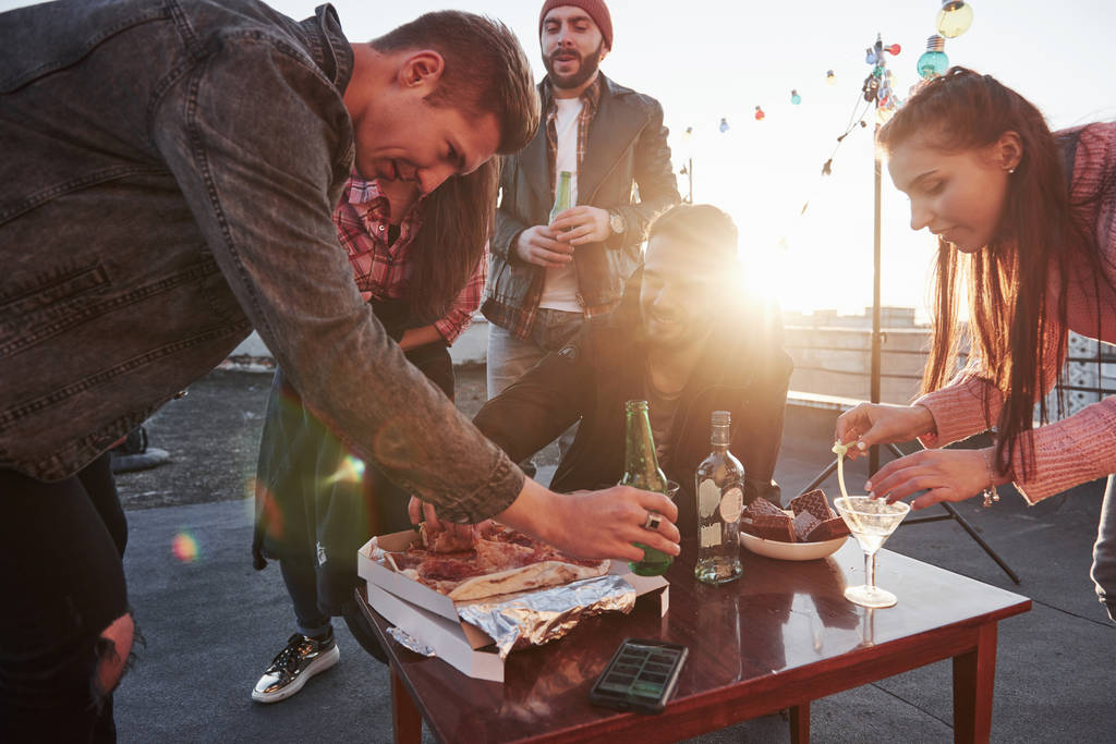 Evening is coming. That sunshine create warm atmosphere. Eating pizza at the rooftop party. Good friends have weekend with some delicious food and alcohol. - Photo, Image