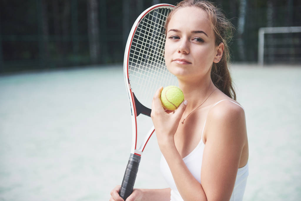 Una mujer bonita usando una cancha de tenis de ropa deportiva en la cancha
. - Foto, Imagen