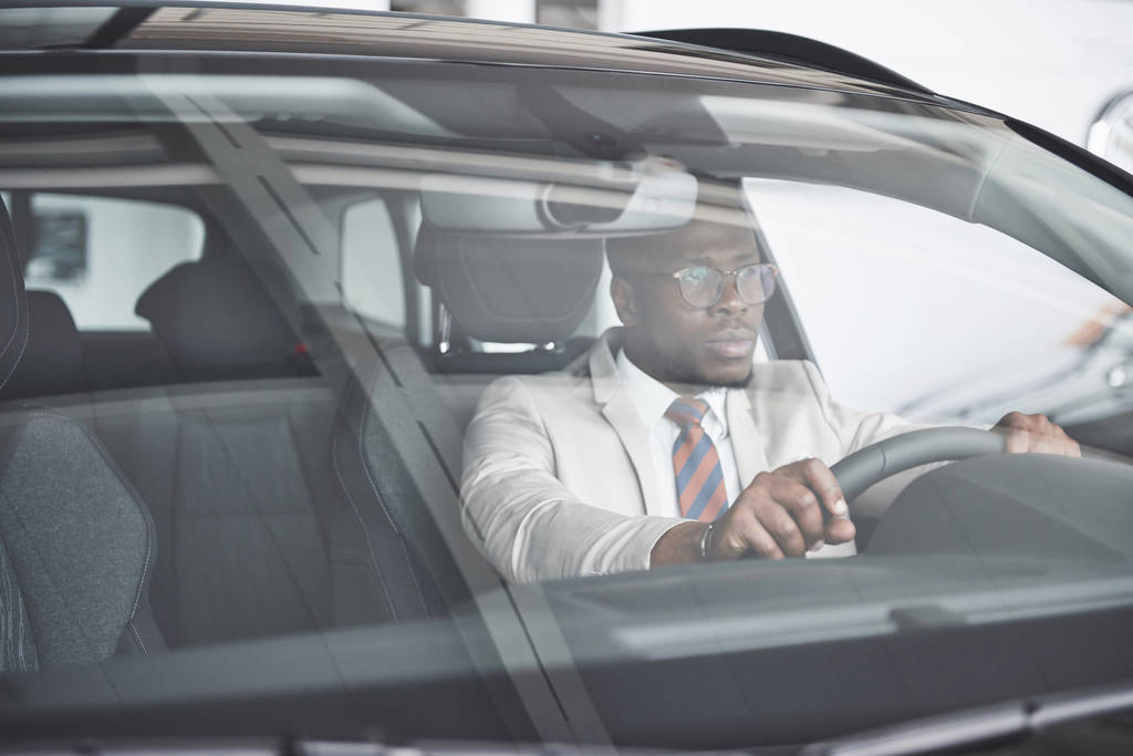 vista frontal de guapo africano elegante serio hombre de negocios conduce un coche
. - Foto, imagen