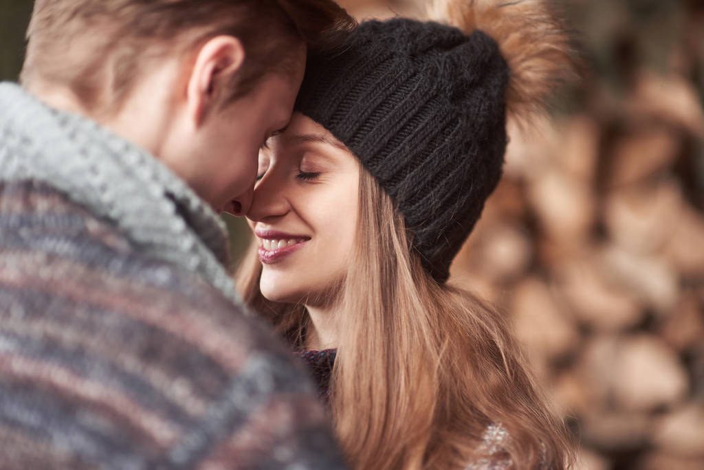 Cintura-se retrato de homem e mulher jovem despreocupado abraçando e sorrindo. Eles estão em pé na floresta de inverno e olhando para a câmera com felicidade
. - Foto, Imagem