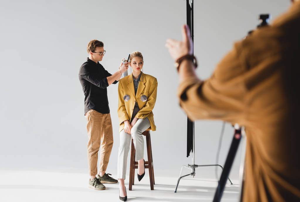 selectieve focus van hairstylist doen kapsel model en fotograaf op backstage - Foto, afbeelding