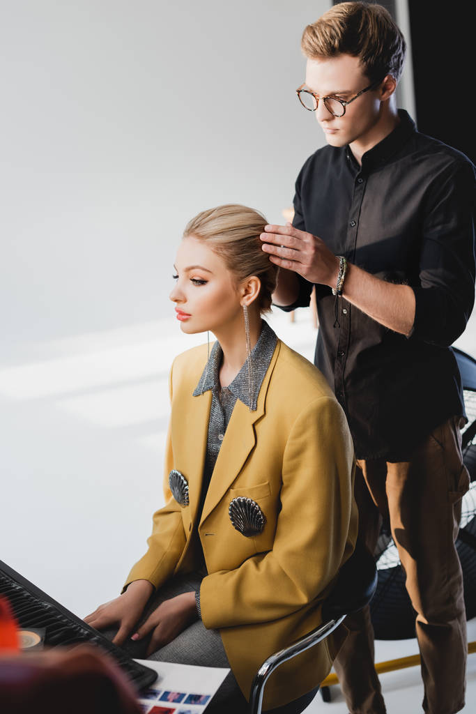 guapo peluquero haciendo peinado a modelo con estilo en el backstage
   - Foto, imagen