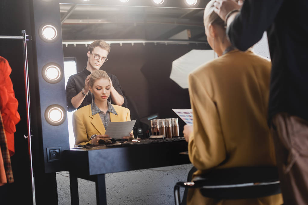 selectieve focus van hairstylist doen kapsel naar stijlvol model op backstage   - Foto, afbeelding