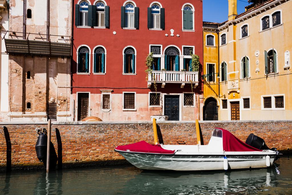 moottorivene kirkkaiden ja värikkäiden rakennusten lähellä Venetsiassa, Italiassa
  - Valokuva, kuva
