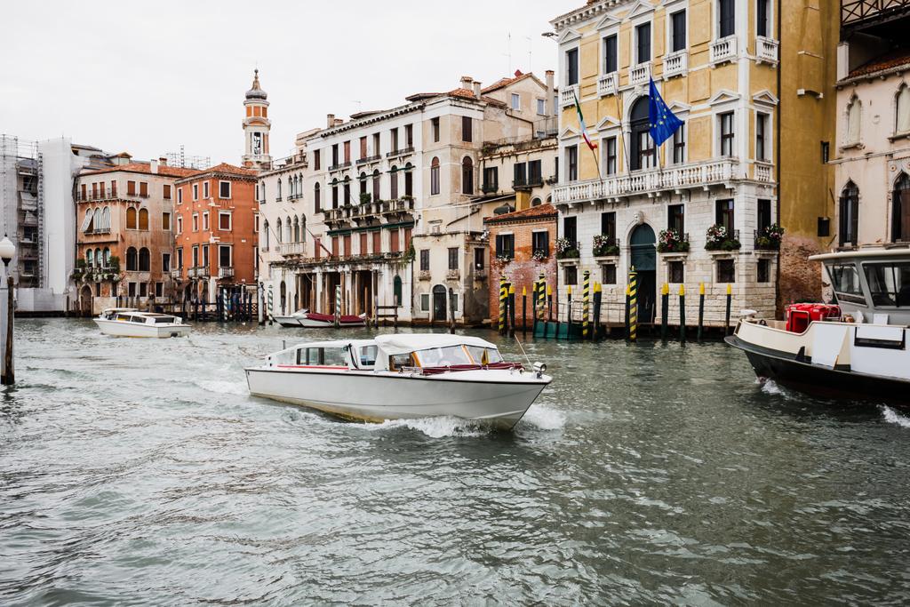 μηχανοκίνητα σκάφη που επιπλέουν στο κανάλι κοντά σε αρχαία κτίρια στη Βενετία, Ιταλία  - Φωτογραφία, εικόνα