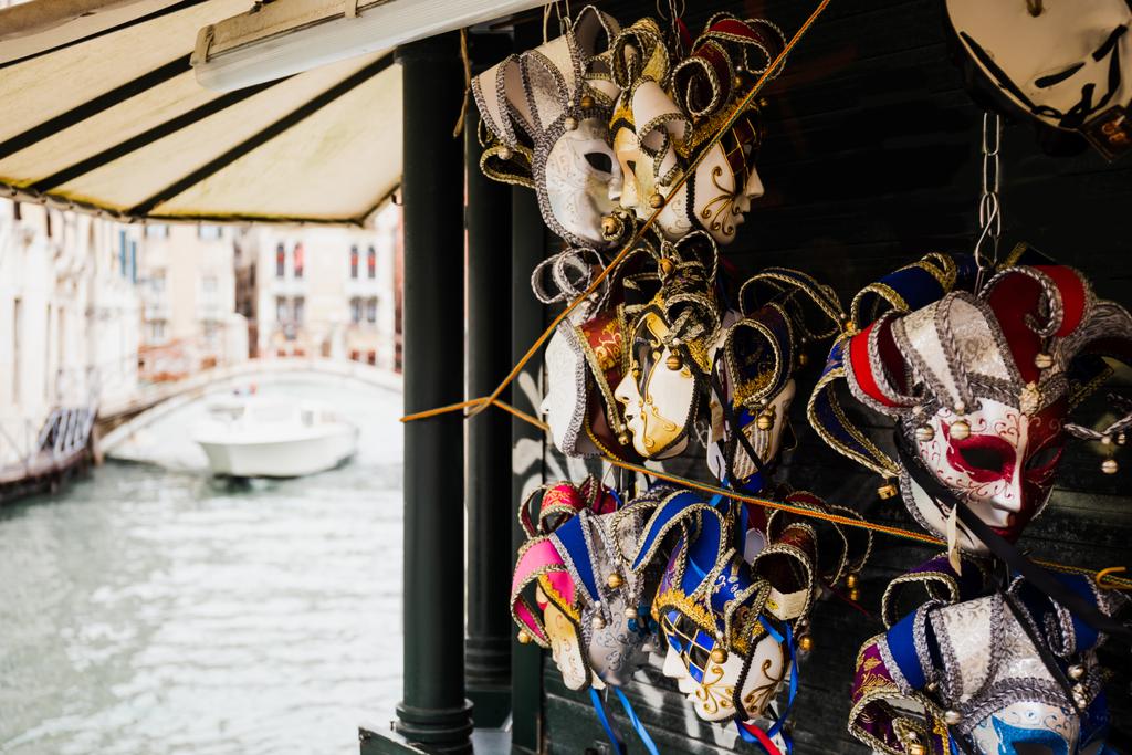 επιλεκτική εστίαση του καρναβαλιού μάσκες και μηχανοκίνητο σκάφος επιπλέουν στο παρασκήνιο στη Βενετία, Ιταλία  - Φωτογραφία, εικόνα