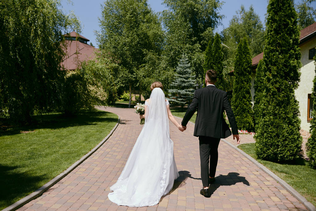 Full length body portrait of young bride and groom walking on ga - Photo, Image