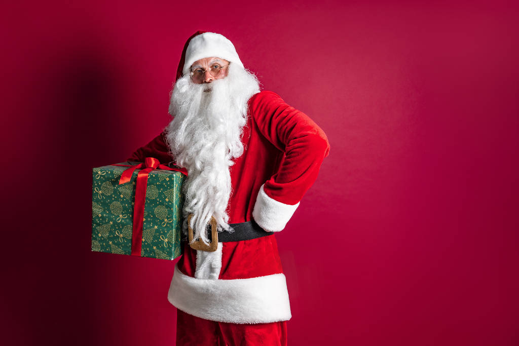 Photo of kind Santa Claus giving xmas present and looking at camera - Photo, Image