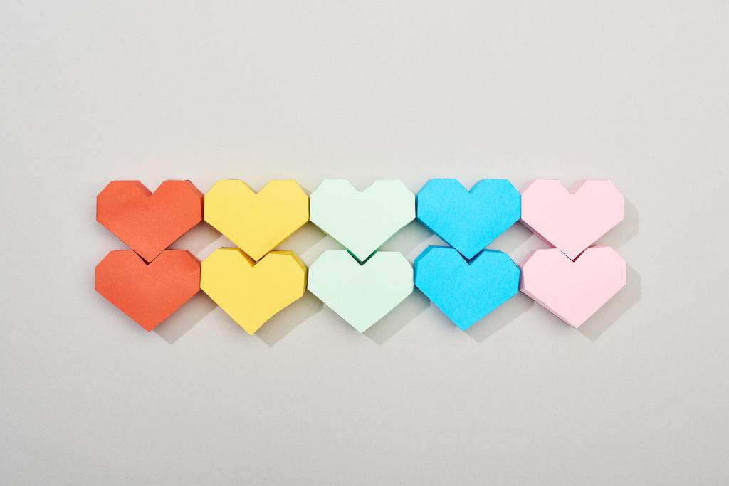 Верхний вид цветных бумажных сердец на сером фоне
 - Фото, изображение