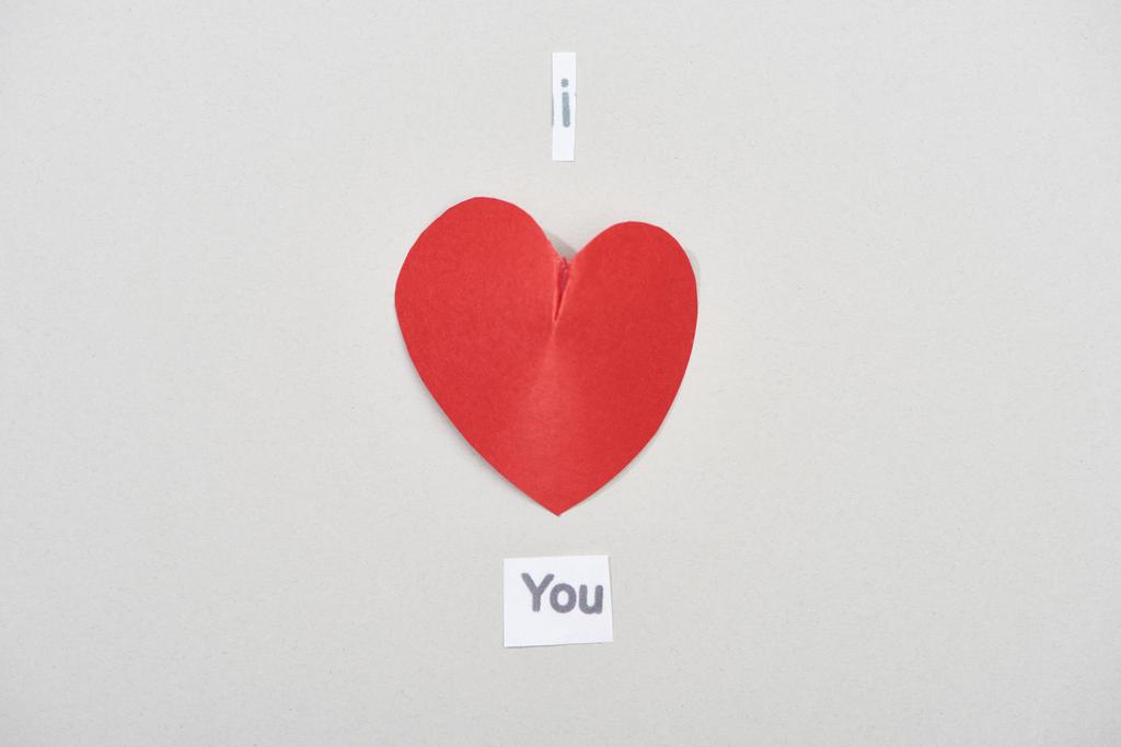 Bovenaanzicht van ik hou van je belettering met papieren hart op grijze achtergrond - Foto, afbeelding