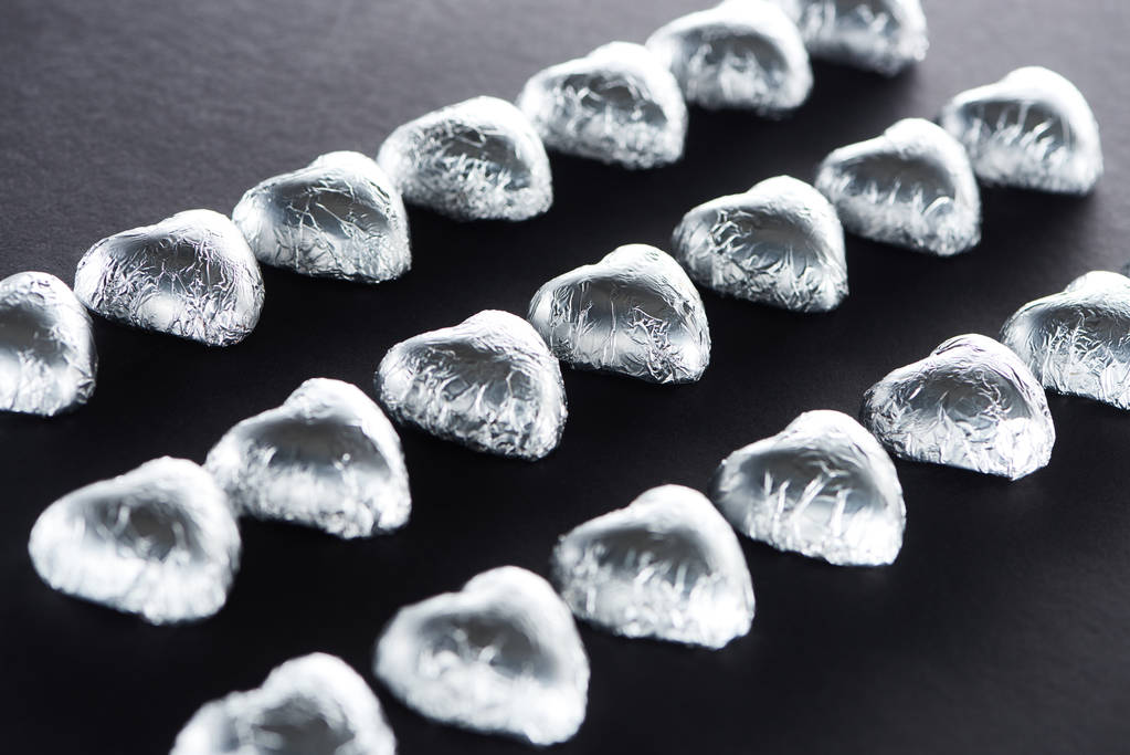 Heart shaped candies in foil on black background - Photo, Image