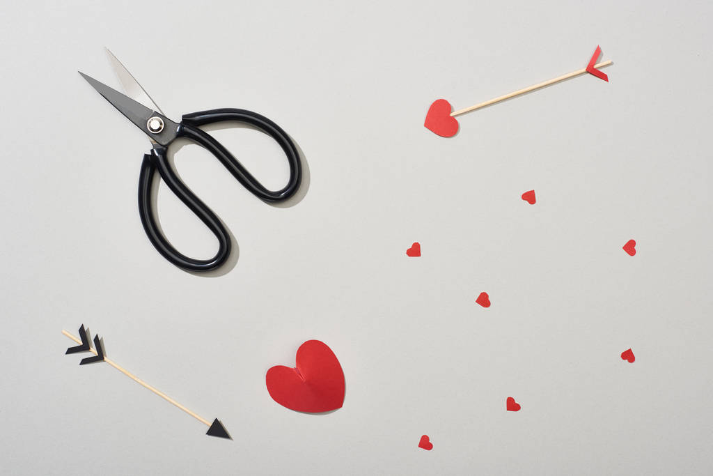 Top view of arrows, scissors and paper hearts on grey background - Photo, Image