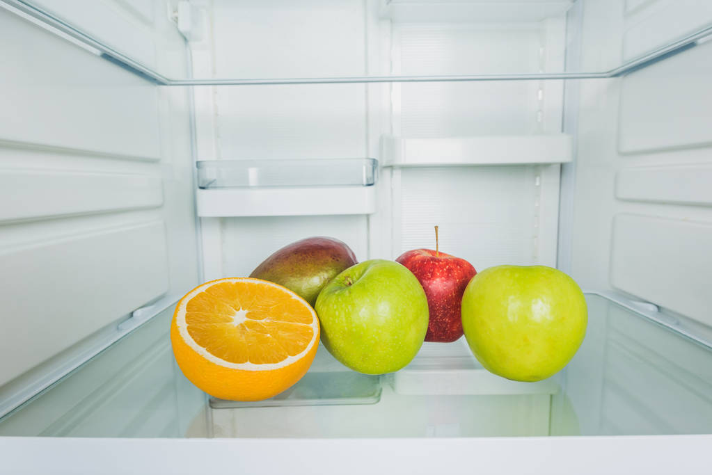 冷蔵庫の棚にマンゴーとオレンジのスライスと新鮮なリンゴ  - 写真・画像