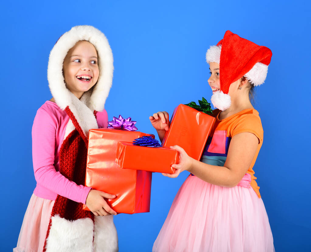 Las chicas abren regalos de Navidad. Hermanas en los sombreros de Santa Claus
 - Foto, imagen