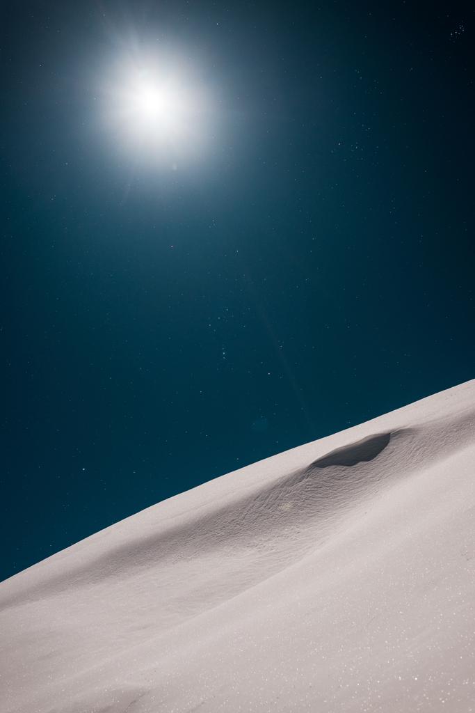 雪に覆われた山の景色と暗い空に輝く太陽 - 写真・画像