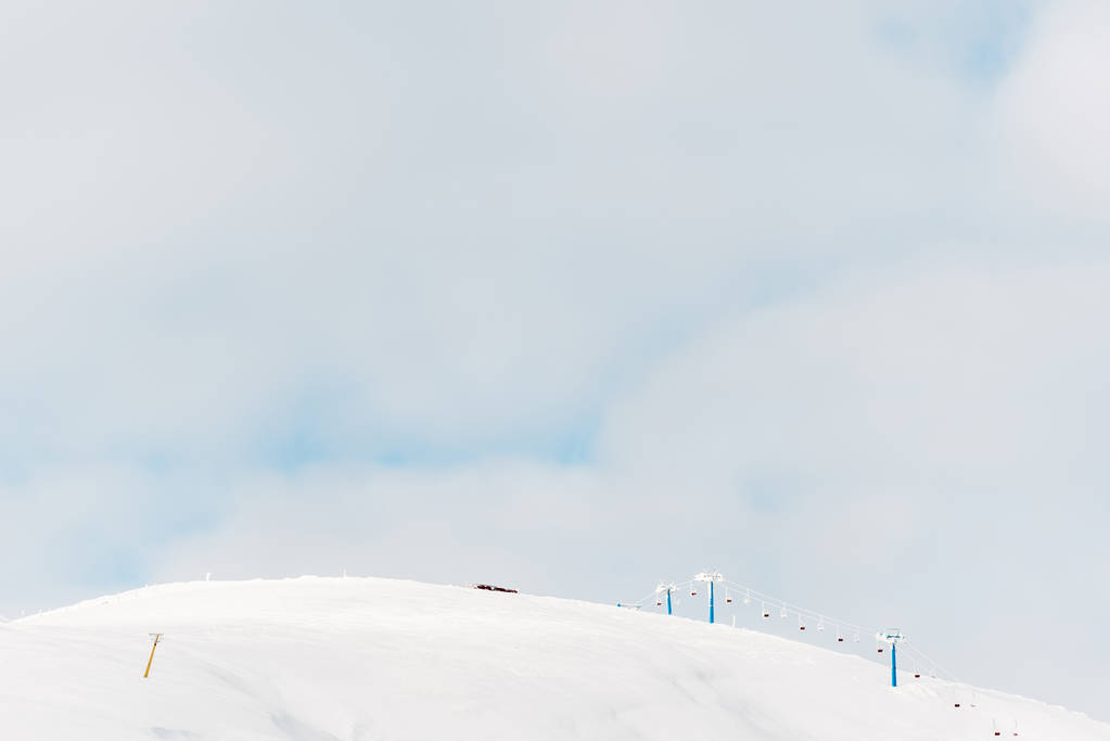 мальовничий вид на засніжену гору з підйомом гондоли і білими пухнастими хмарами в небі
 - Фото, зображення