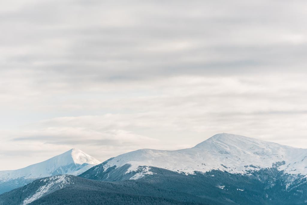 мальовничий вид на засніжені гори в білих пухнастих хмарах
 - Фото, зображення
