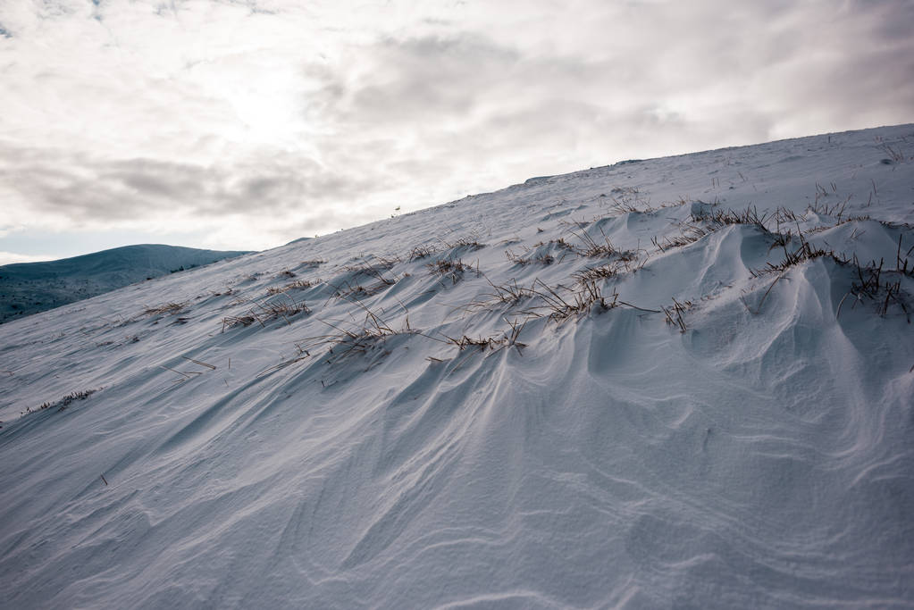 malerischer Blick auf den verschneiten Hügel mit bewölktem Himmel auf dem Hintergrund - Foto, Bild