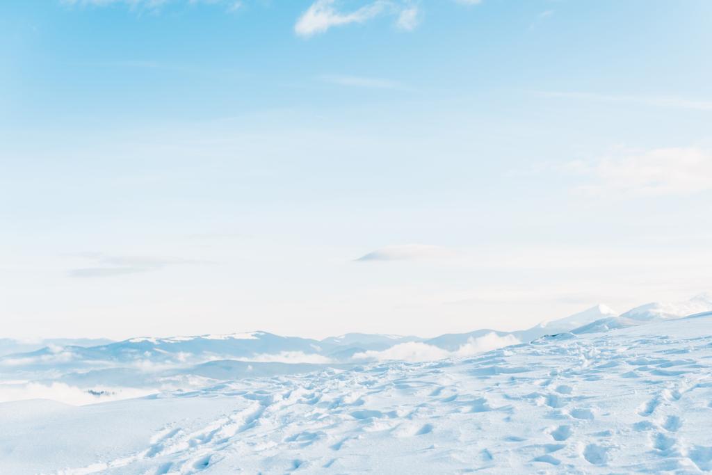 malowniczy widok na zaśnieżoną górę ze śladami i czystym błękitnym niebem - Zdjęcie, obraz