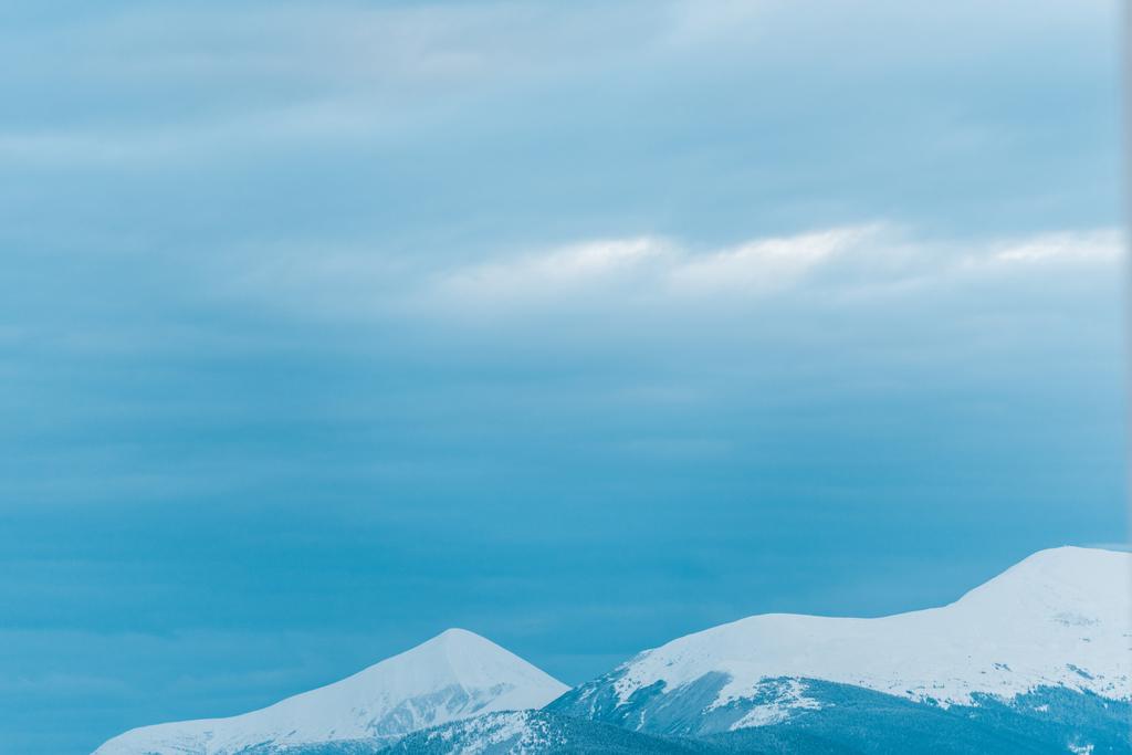 malowniczy widok na zaśnieżone góry z białym zachmurzonym niebem - Zdjęcie, obraz
