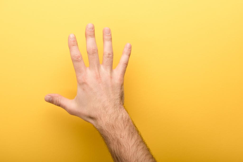 cropped view of man showing five fingers on yellow background  - Photo, Image