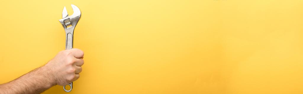 panoráma lövés férfi gazdaság csavarkulcs sárga háttér  - Fotó, kép