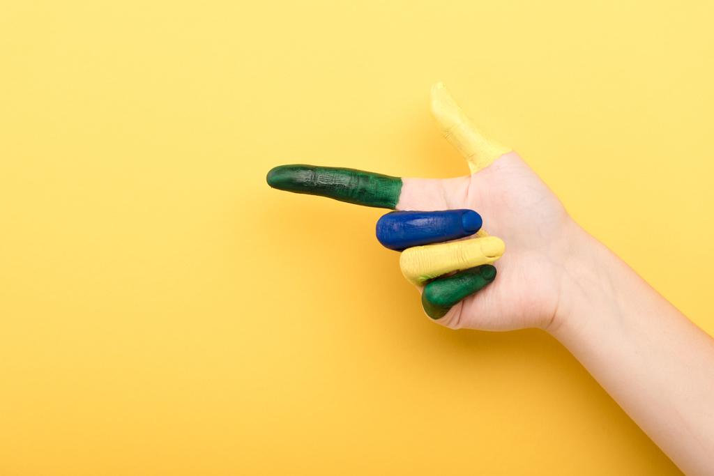 abgeschnittene Ansicht einer Frau, die mit dem Finger auf gelbem Hintergrund zeigt  - Foto, Bild