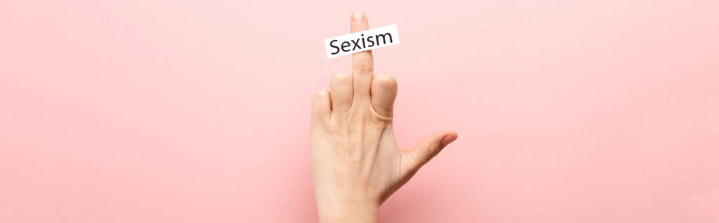 panoramic shot of woman showing middle finger and card with sexism lettering on pink background  - Photo, Image
