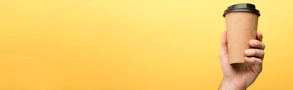 панорамный снимок человека, держащего бумажную чашку на желтом фоне
  - Фото, изображение