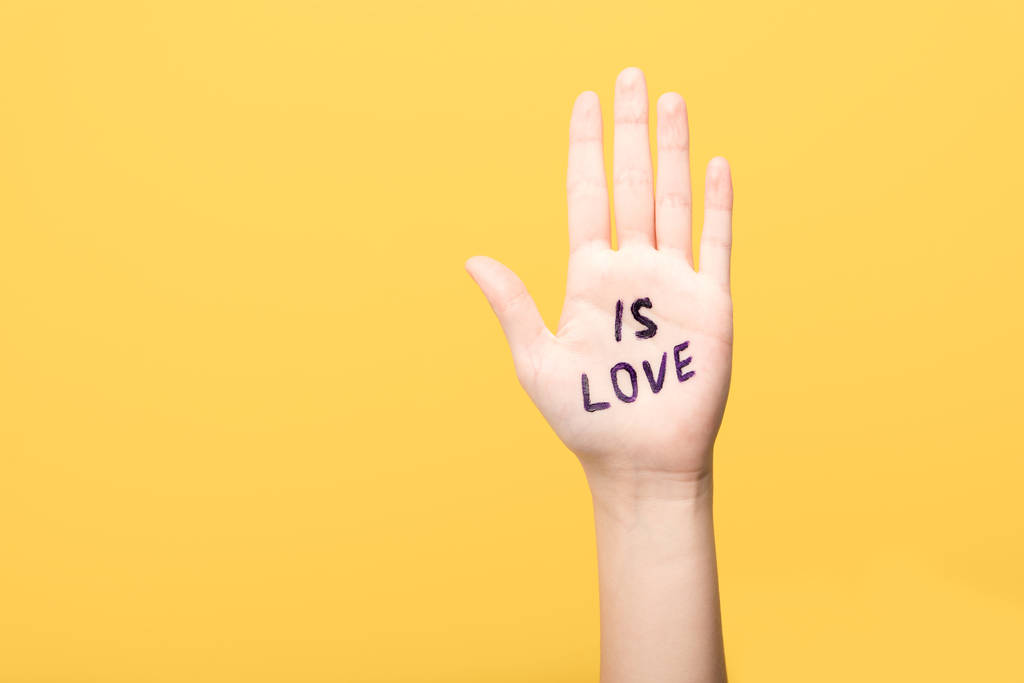 abgeschnittene Ansicht einer Frau mit Liebes-Schriftzug auf der Hand isoliert auf gelb - Foto, Bild