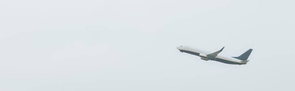 Low angle view van het vliegtuig in de bewolkte lucht, panoramisch schot - Foto, afbeelding