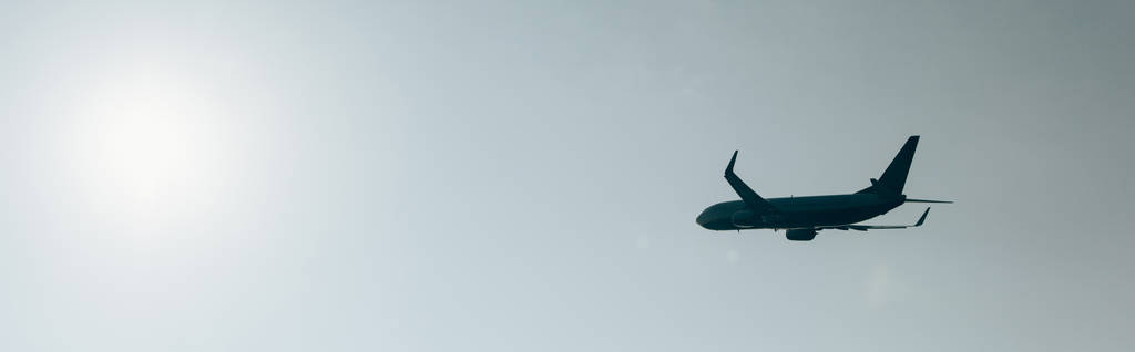 Nízký úhel pohledu na letadlo s jasnou oblohou a sluncem na pozadí, panoramatický záběr - Fotografie, Obrázek