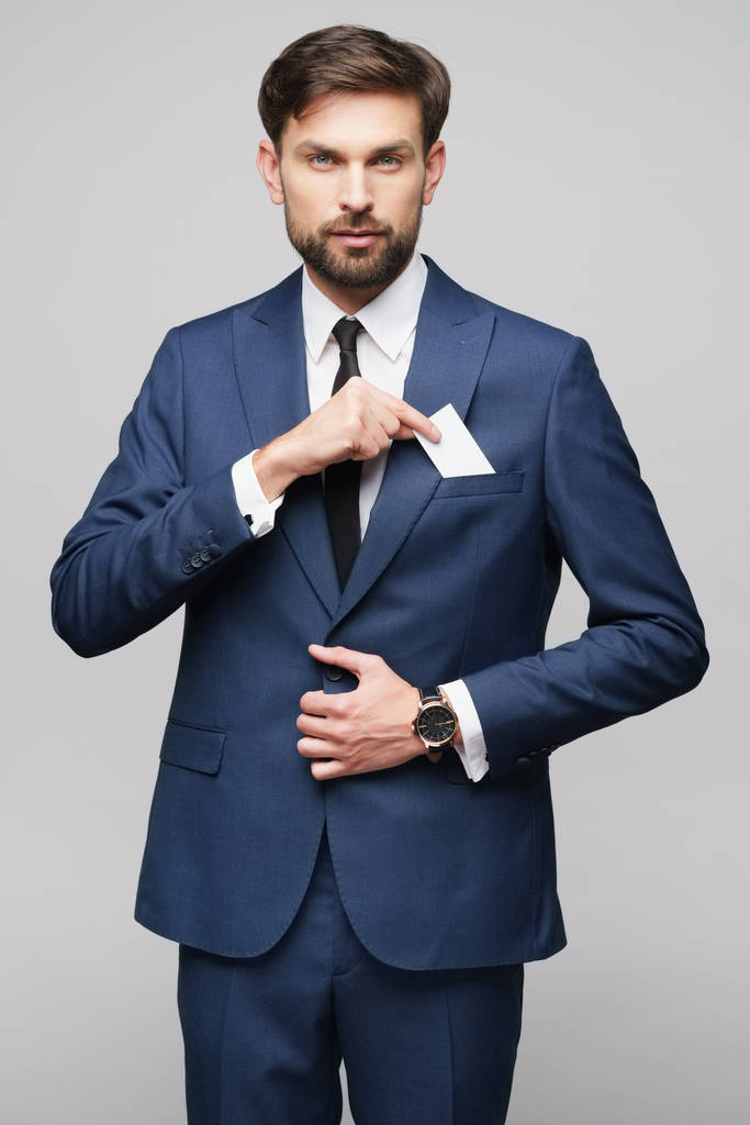 studio photo of young handsome businessman wearing suit holding business card - Photo, Image