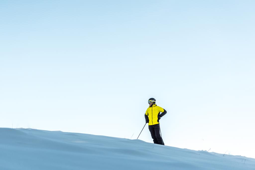 лыжник в шлеме держа палки, стоя с рукой на бедре
  - Фото, изображение