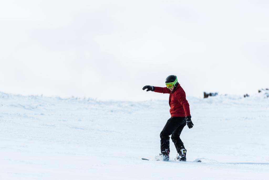 snowboardzista sportowy w kasku i goglach jeżdżący na stoku na zewnątrz  - Zdjęcie, obraz