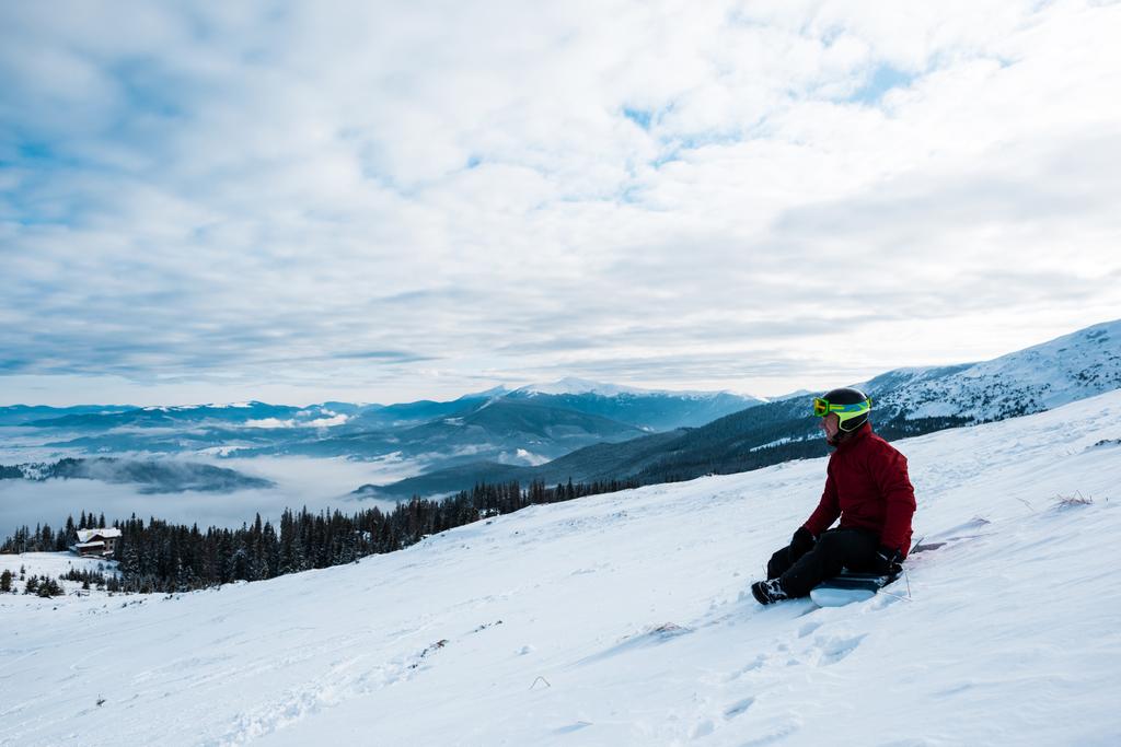 сноубордист у шоломі сидить на схилі блакитного неба
  - Фото, зображення