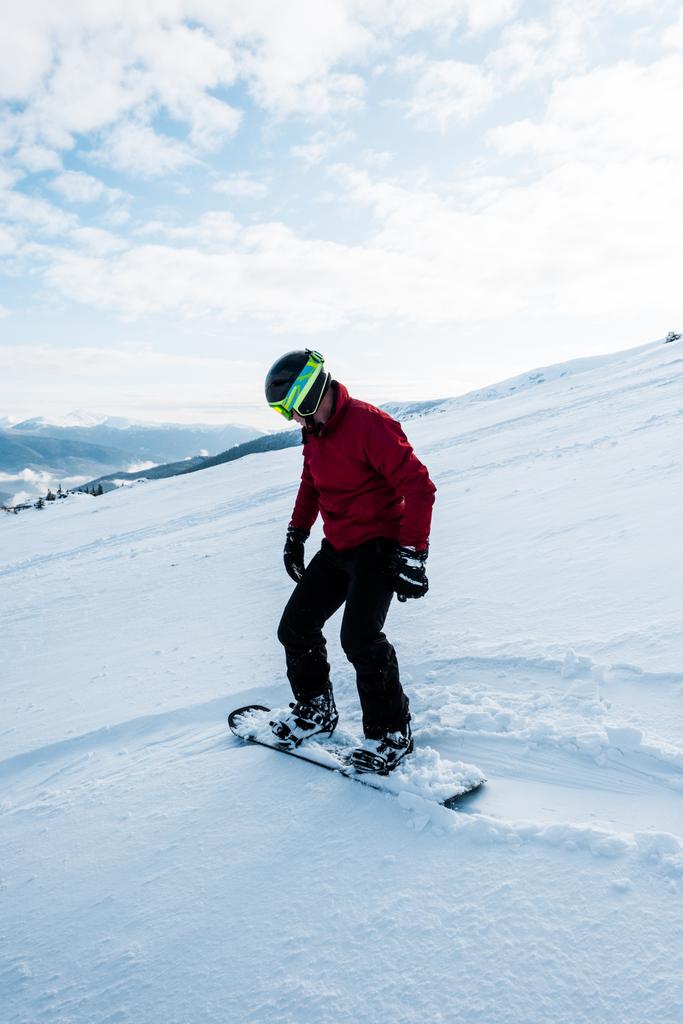 冬には白い雪と一緒に斜面に乗るヘルメットのスノーボーダー  - 写真・画像