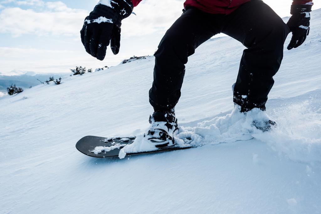 vista recortada de snowboarder en guantes montados en pendiente con nieve blanca en invierno
  - Foto, imagen