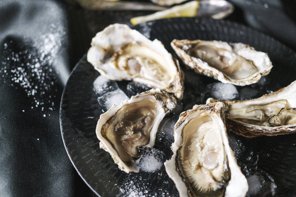 Open oysters with lemon in a black plate - Photo, Image