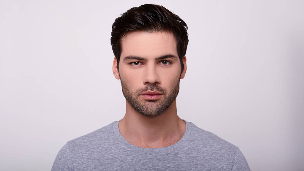 Porträt eines jungen, gutaussehenden Mannes in einem grauen T-Shirt. - Foto, Bild