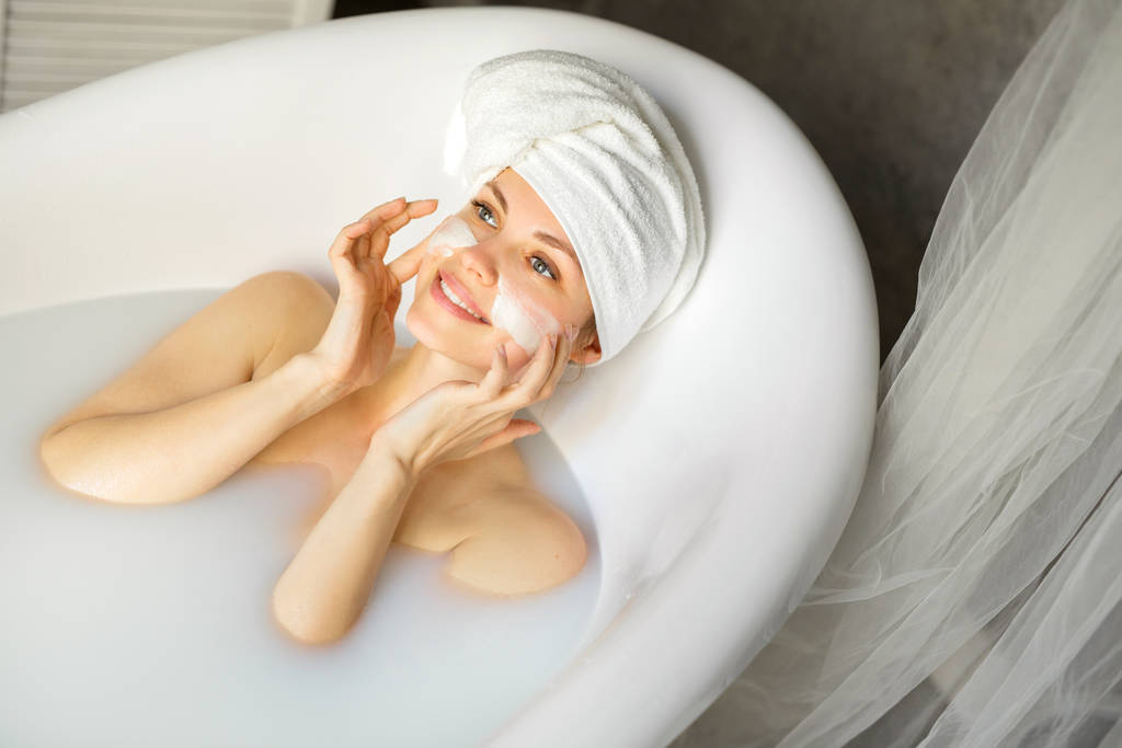 kaunis nuori nainen pyyhe päässään, makaa kylvyssä maidon kanssa
 - Valokuva, kuva