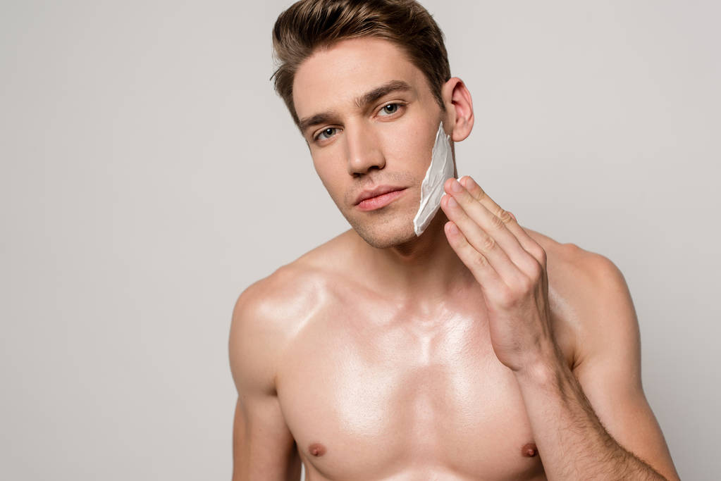 sexy hombre con torso muscular aplicación de espuma de afeitar aislado en gris
 - Foto, imagen