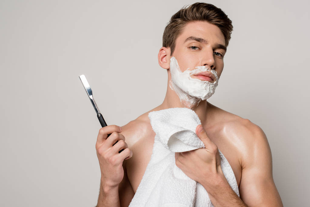 szexi férfi izmos törzs és borotválkozás hab az arcon gazdaság egyenes borotva és törölköző elszigetelt szürke - Fotó, kép