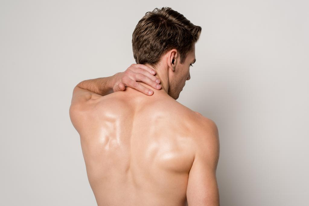 Rückenansicht eines Mannes mit Nackenschmerzen isoliert auf grau - Foto, Bild